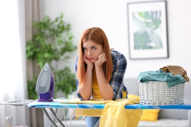 Tired housewife ironing clothes at home