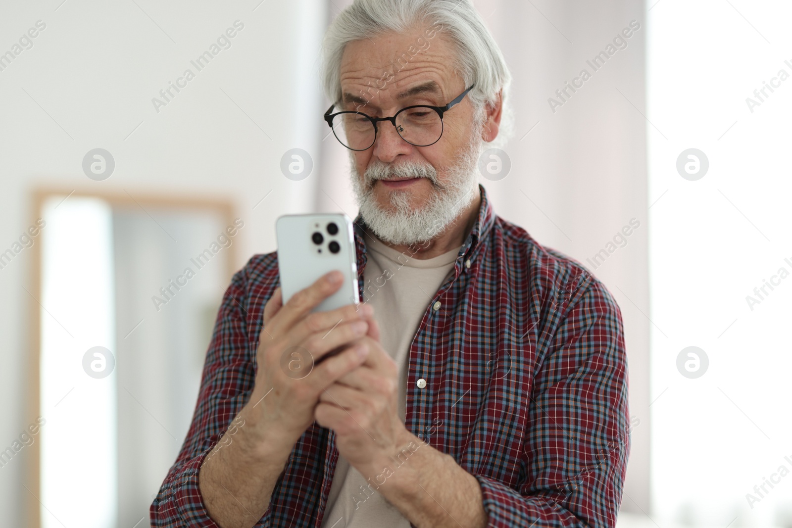 Photo of Portrait of happy grandpa with glasses using smartphone indoors