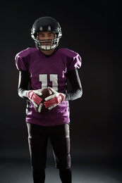 Photo of American football player with ball on dark background