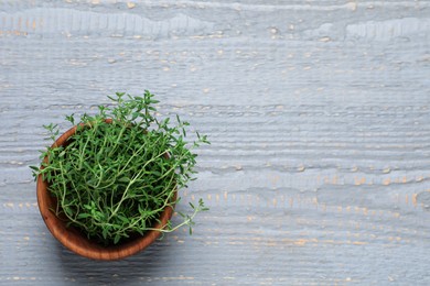 Bowl of aromatic thyme on grey wooden table, top view. Space for text