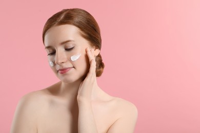 Photo of Beautiful woman with freckles and cream on her face against pink background. Space for text