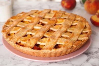Photo of Delicious peach pie and fresh fruits on white marble table, closeup