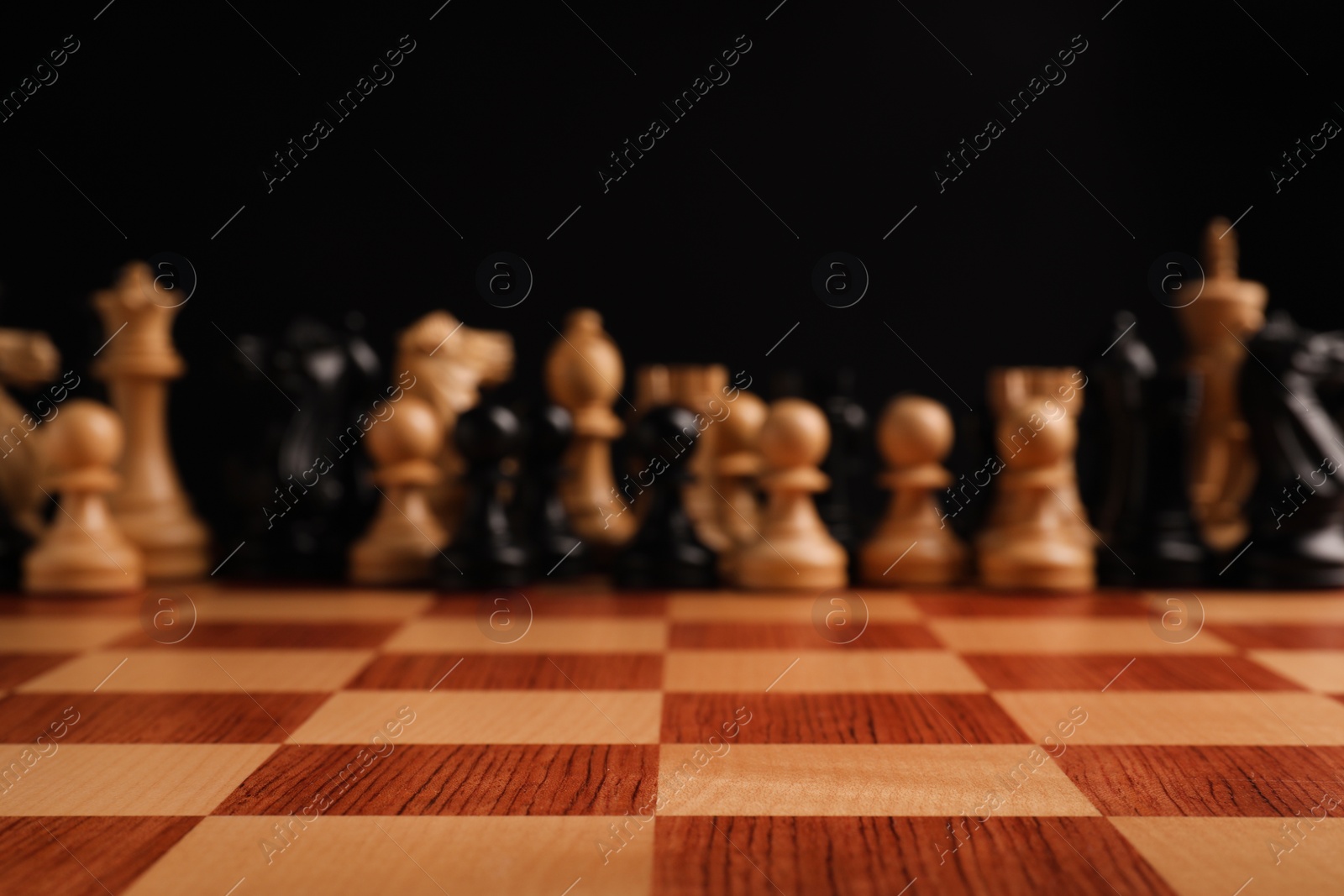 Photo of Many chess pieces on wooden checkerboard against black background, selective focus