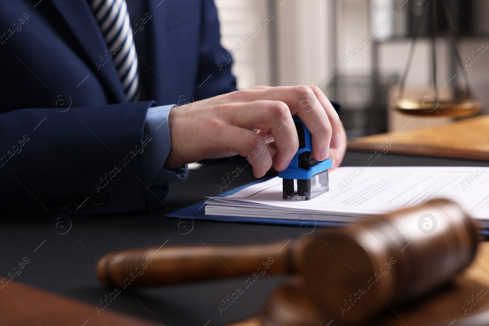 Photo of Notary stamping document at table in office, closeup