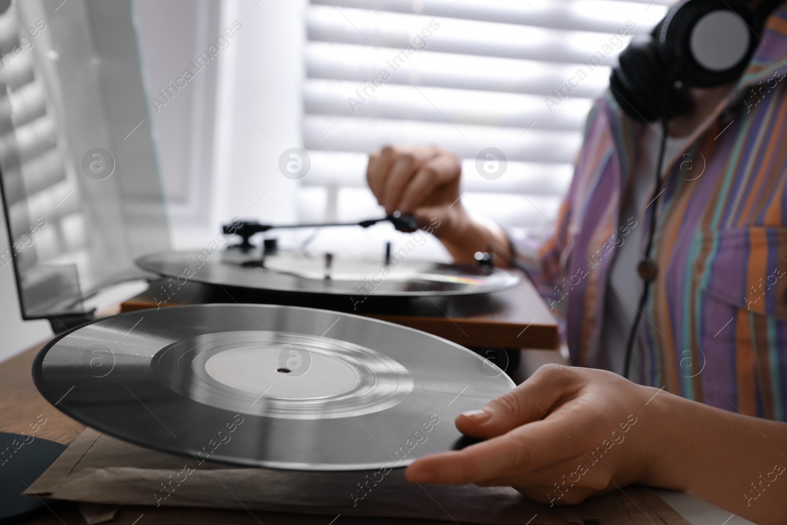 Photo of Young woman using turntable at home, closeup