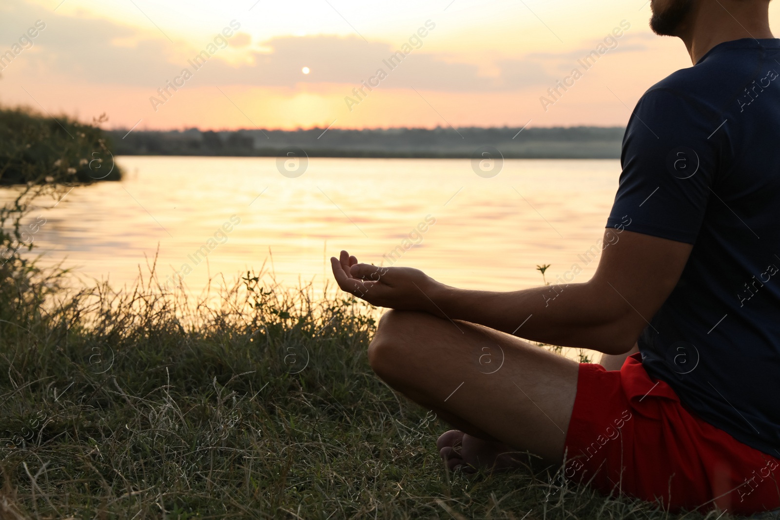 Photo of Man meditating near river at sunset, closeup. Space for text