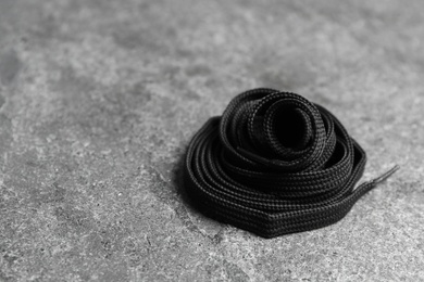 Photo of Black shoelace on grey stone background. Space for text