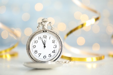 Pocket watch on table against blurred lights, space for text. New Year countdown