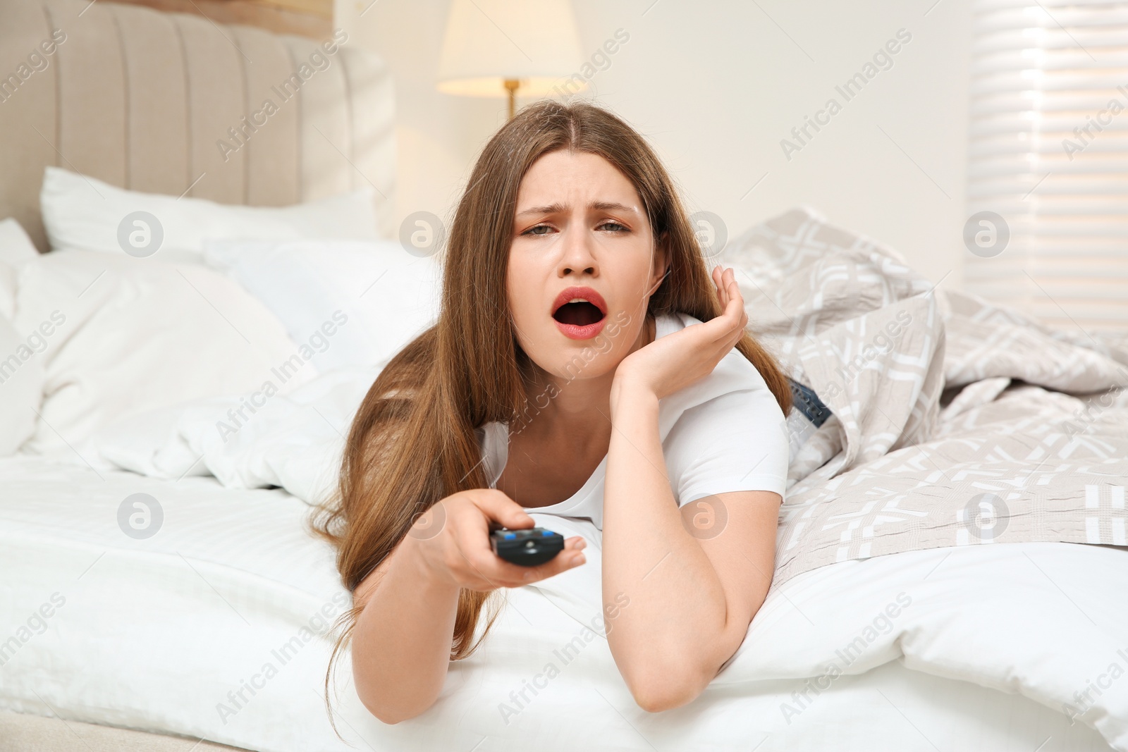 Photo of Lazy young woman watching TV in bedroom