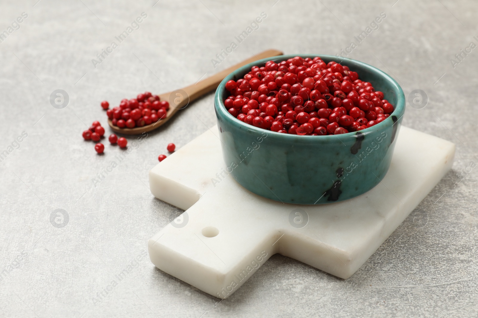 Photo of Aromatic spice. Red pepper in bowl and spoon on light textured table, closeup. Space for text