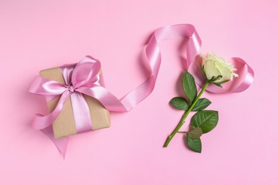 Gift box and beautiful rose flower on pink background, flat lay