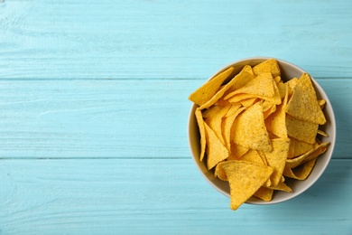 Tasty mexican nachos chips in bowl on blue wooden table, top view. Space for text