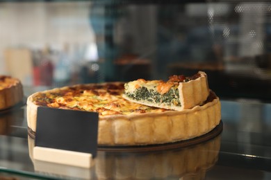 Delicious quiche with salmon and spinach on counter in bakery shop, closeup. Space for text