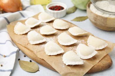 Photo of Raw dumplings (varenyky) with tasty filling and ingredients on light grey table