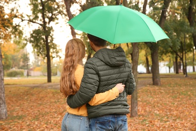 Photo of Happy couple with umbrella walking in park