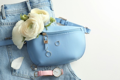 Photo of Flat lay composition with stylish bump bag and spring flowers on light background. Space for text