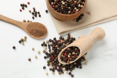 Photo of Aromatic spice. Different peppers in bowl, scoop and spoon on white table, flat lay