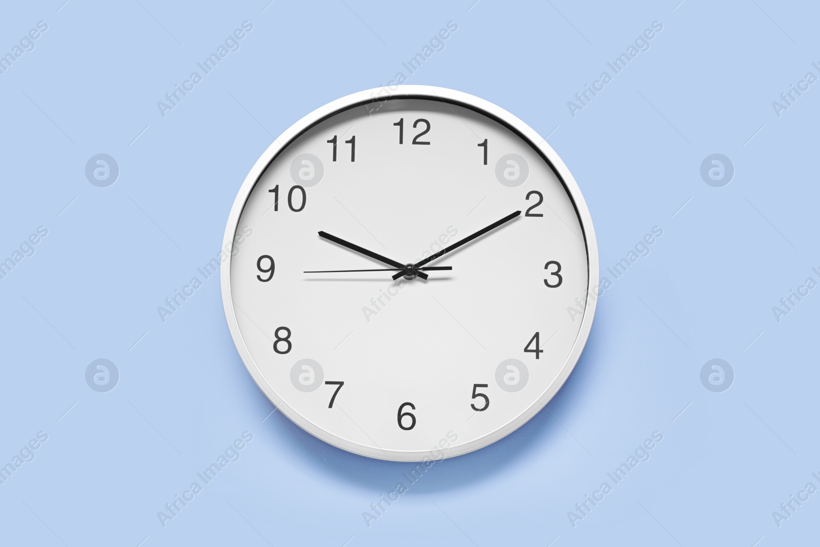 Photo of Stylish round clock on light blue background, top view. Interior element