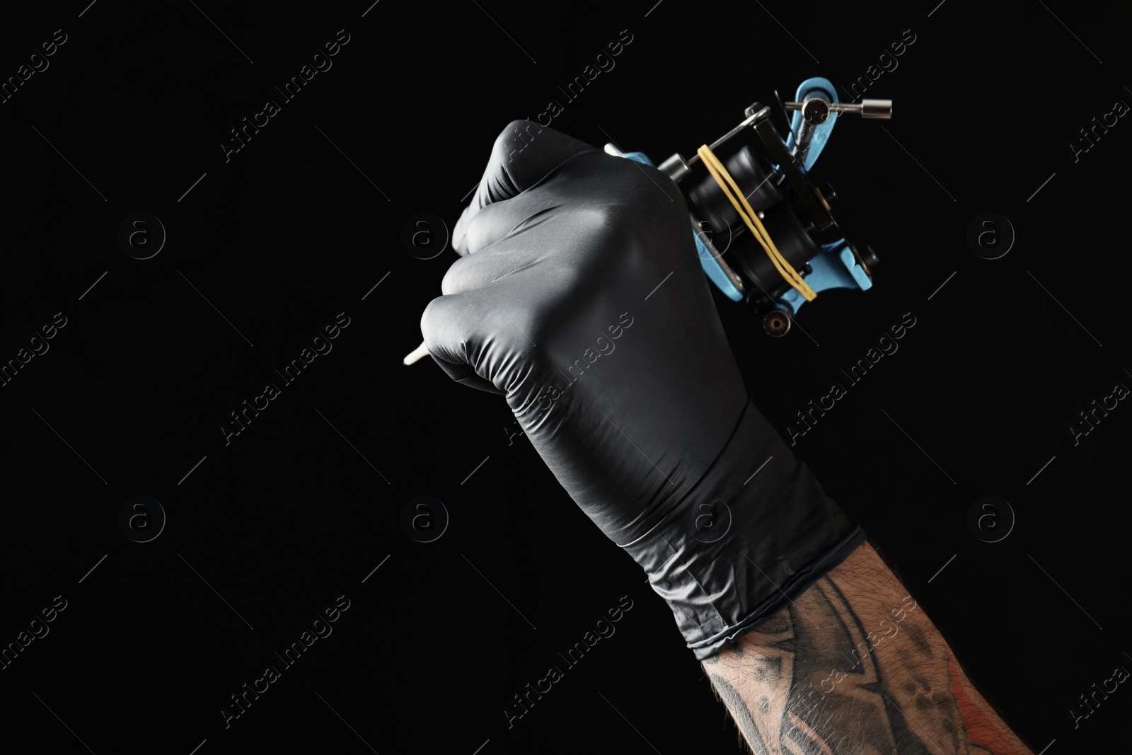 Photo of Professional tattoo artist with machine on black background, closeup. Space for text