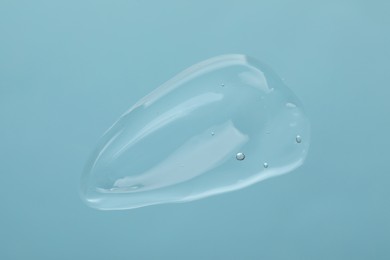 Photo of Sample of cleansing gel on light blue background, top view. Cosmetic product