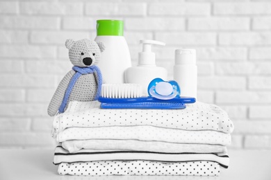 Baby accessories on table near white brick wall