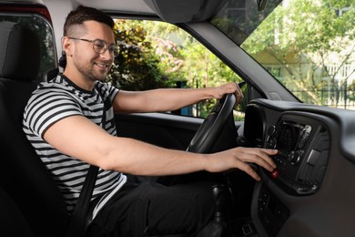 Photo of Choosing favorite radio. Handsome man pressing button on vehicle audio in car