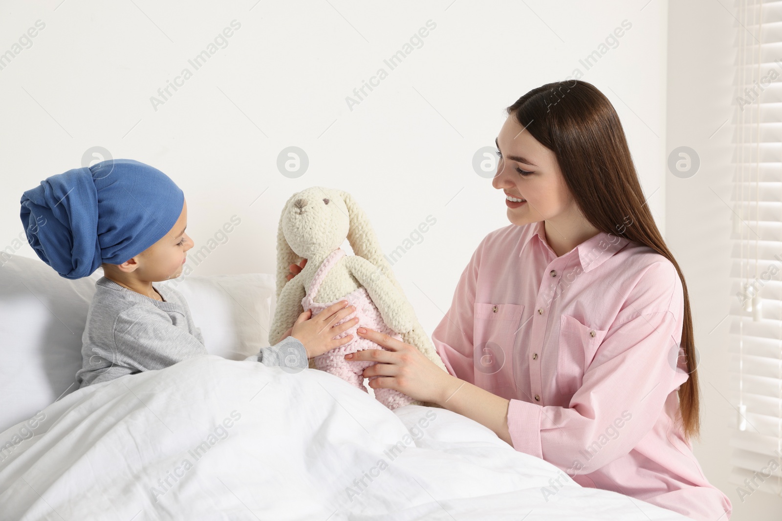 Photo of Childhood cancer. Mother and daughter with toy bunny in hospital