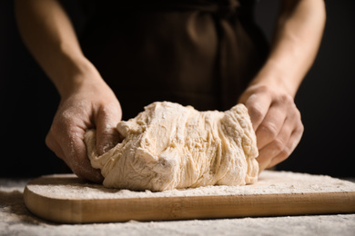 Photo of Woman with dough at grey table, closeup. Making pasta