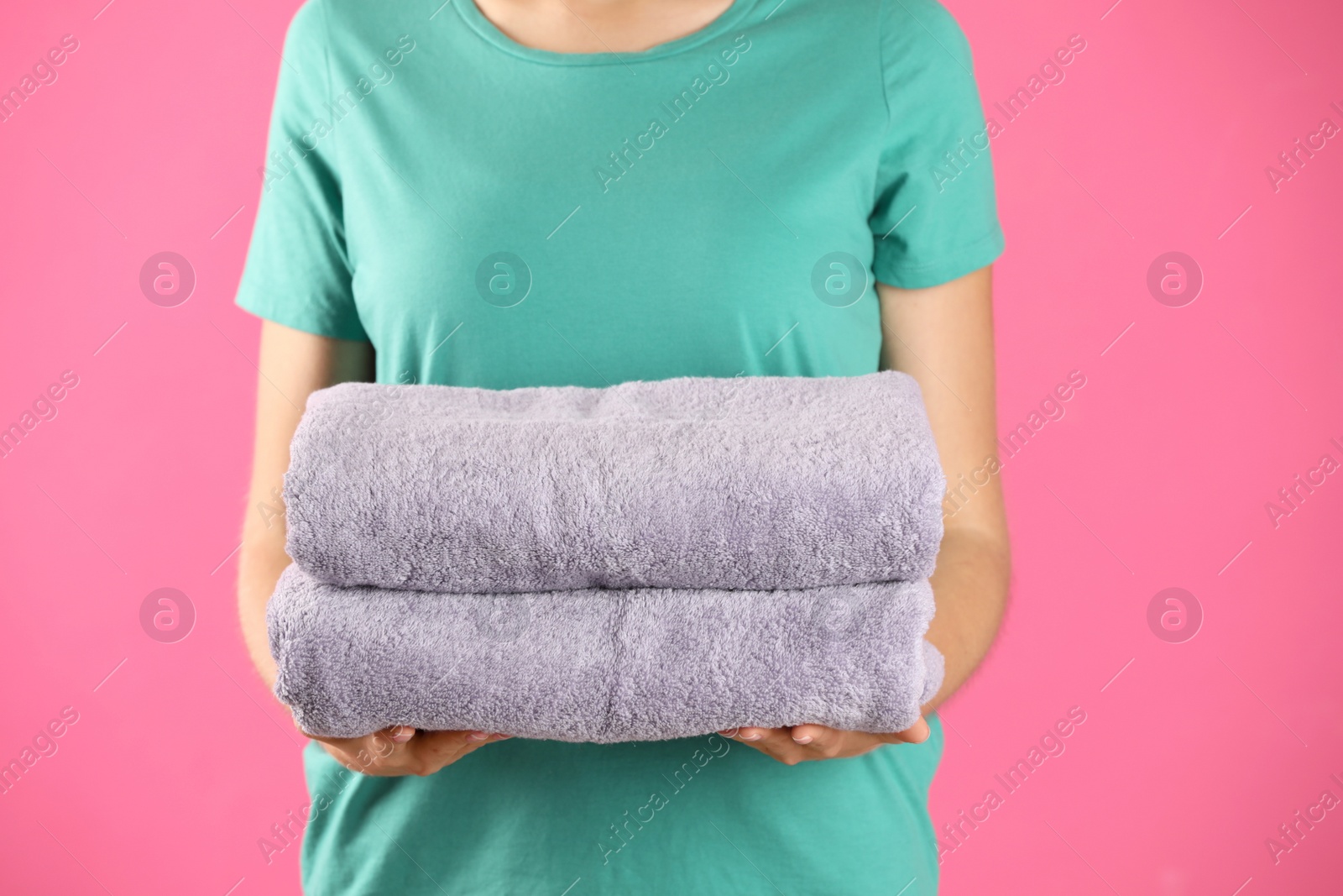 Photo of Woman holding fresh towels on pink background, closeup