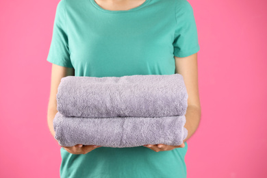 Woman holding fresh towels on pink background, closeup