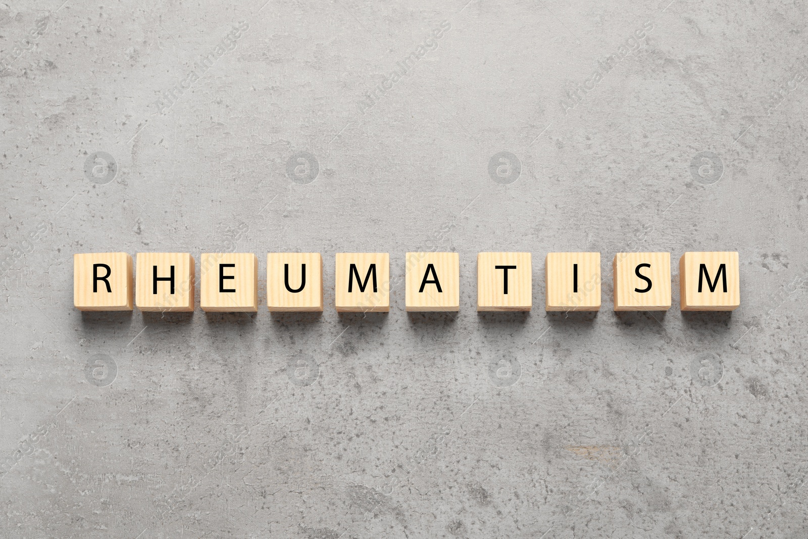 Photo of Word Rheumatism made of wooden cubes on light gray textured background, top view