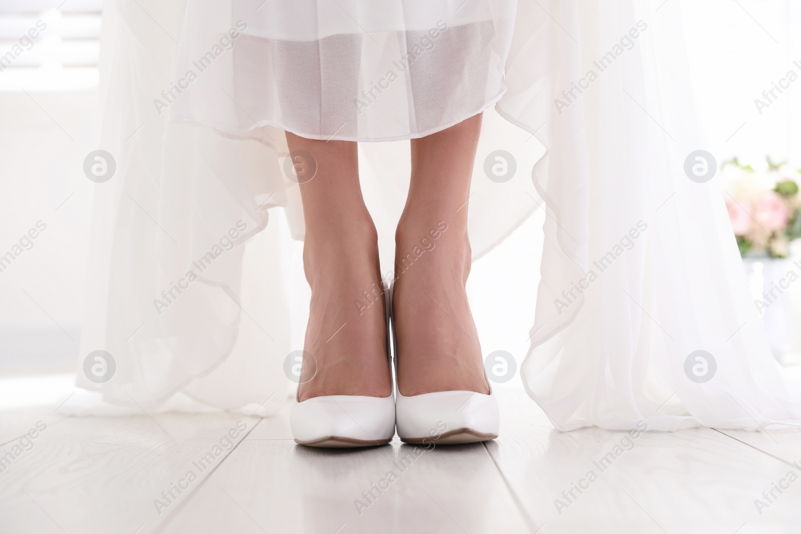 Photo of Young bride wearing beautiful wedding shoes indoors, closeup