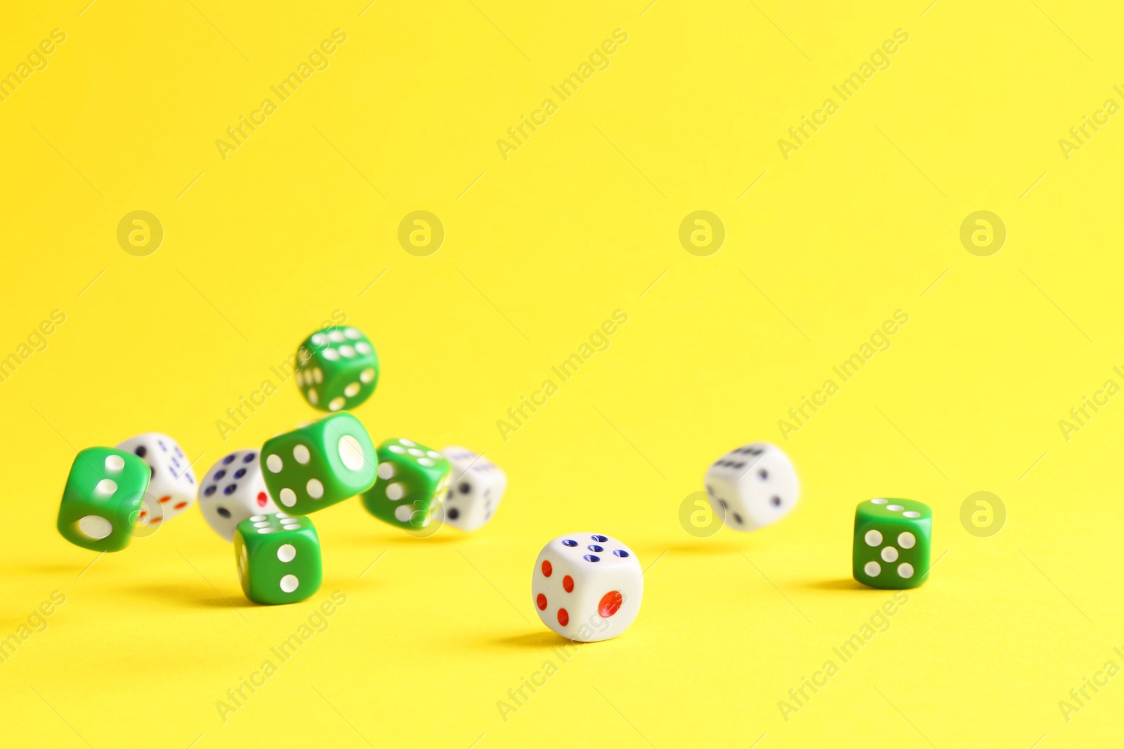 Photo of Many color game dices falling on yellow background