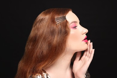 Portrait of beautiful young woman with makeup posing on black background