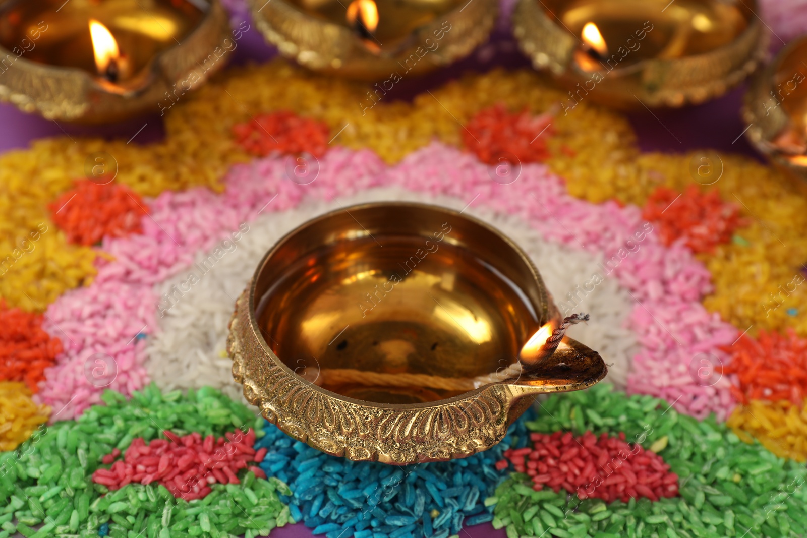 Photo of Diwali celebration. Diya lamps on colorful rangoli, closeup