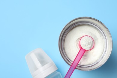 Photo of Flat lay composition with powdered infant formula on light blue background, space for text. Baby milk