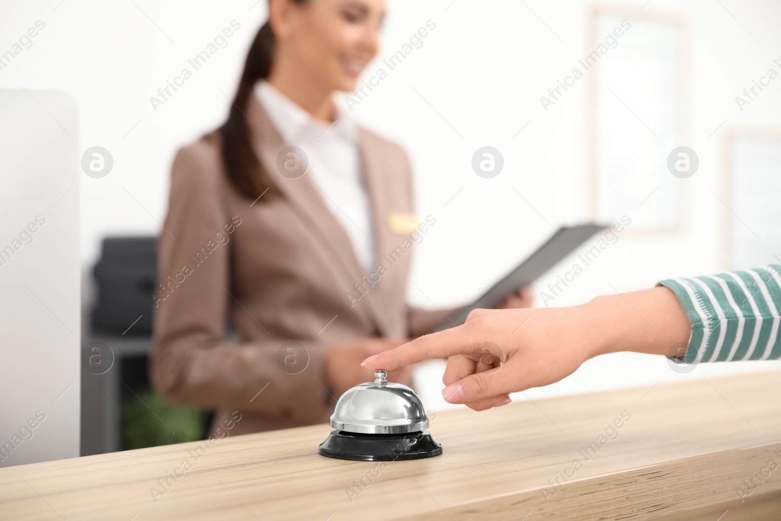 Photo of Guest pressing service bell at desk near receptionist in hotel, closeup. Space for text