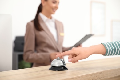 Photo of Guest pressing service bell at desk near receptionist in hotel, closeup. Space for text