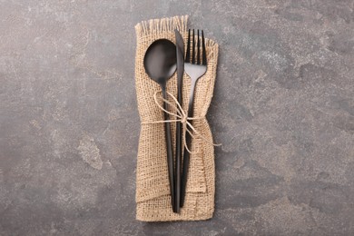 Set of stylish cutlery and napkin on grey textured table, top view