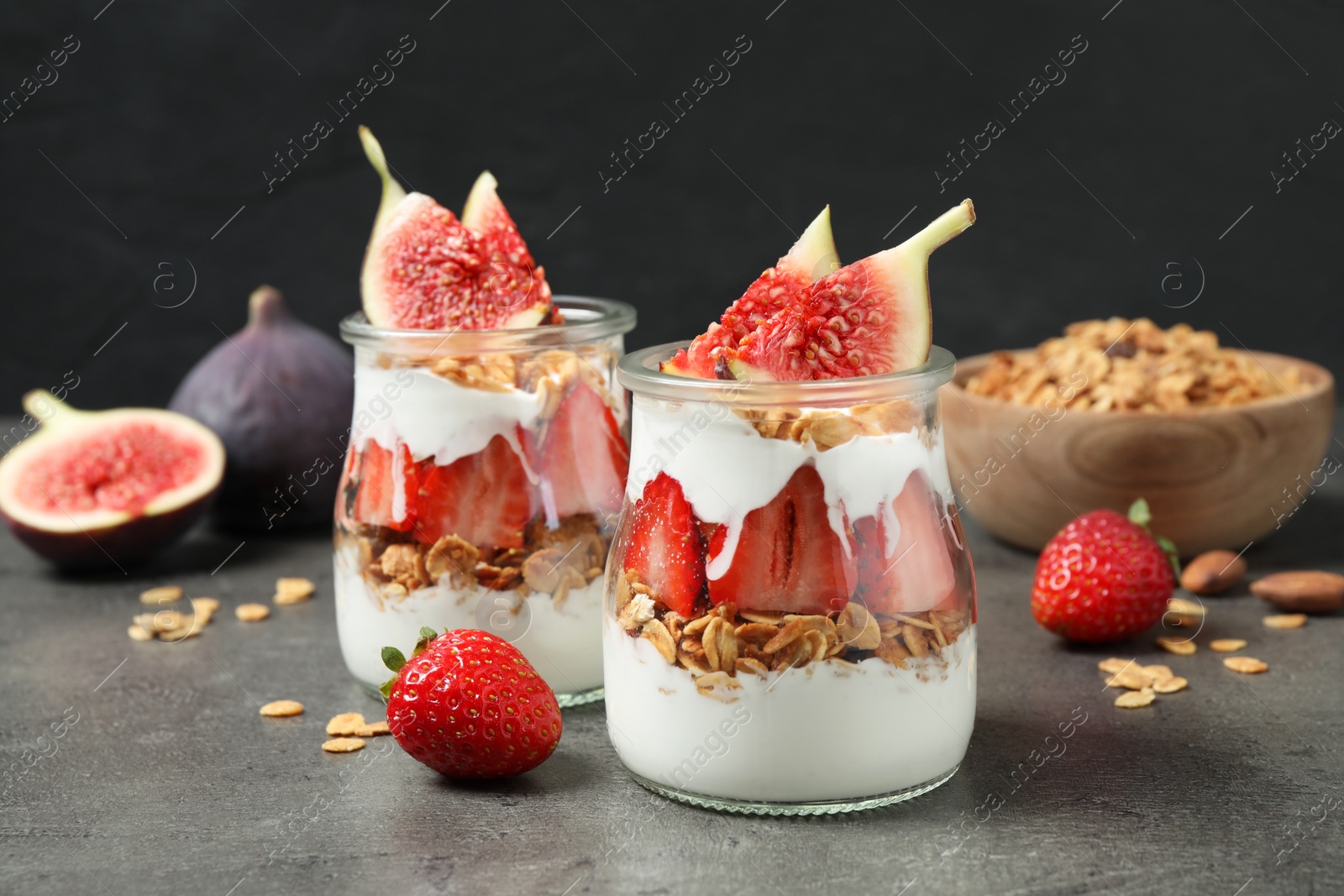 Photo of Jars of tasty homemade granola dessert on grey table. Healthy breakfast