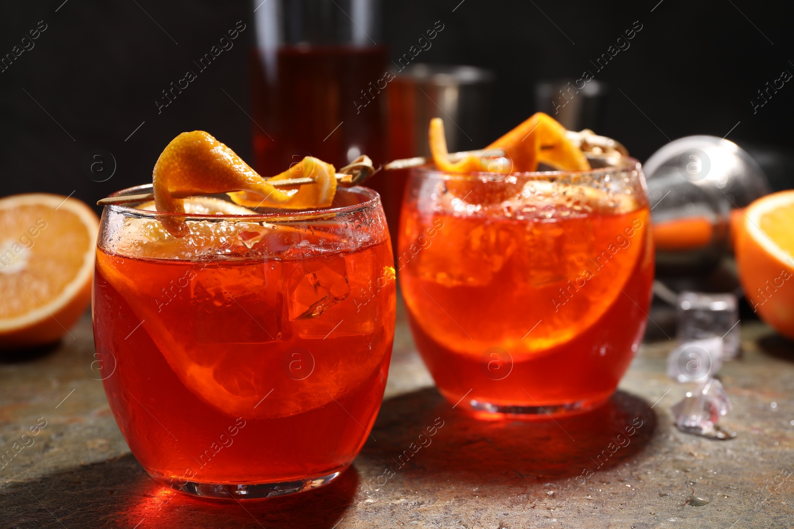 Photo of Aperol spritz cocktail, ice cubes and orange slices in glasses on grey textured table, closeup