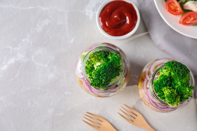 Photo of Healthy salad in glass jars on light table, flat lay. Space for text