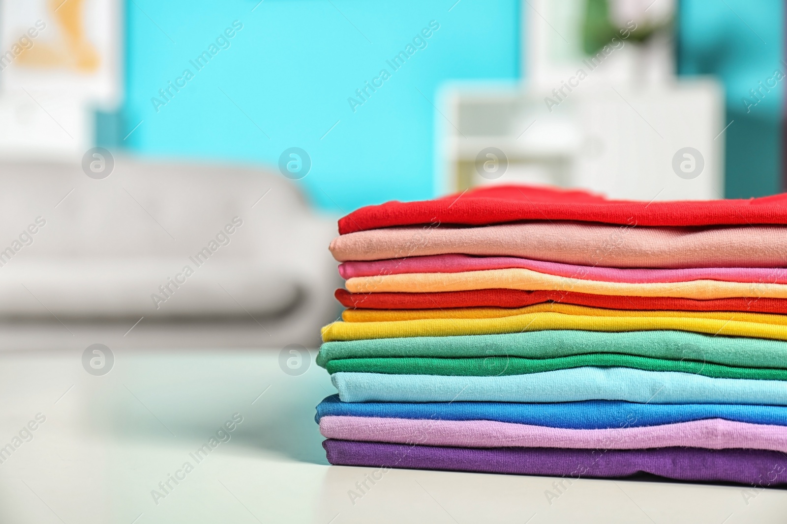 Photo of Stack of colorful t-shirts on table in living room