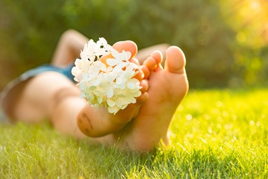 Photo of Teenage girl with beautiful hortensia flowers lying on green grass outdoors, closeup