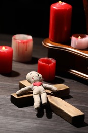 Photo of Voodoo doll with pins in heart and ceremonial items on wooden table