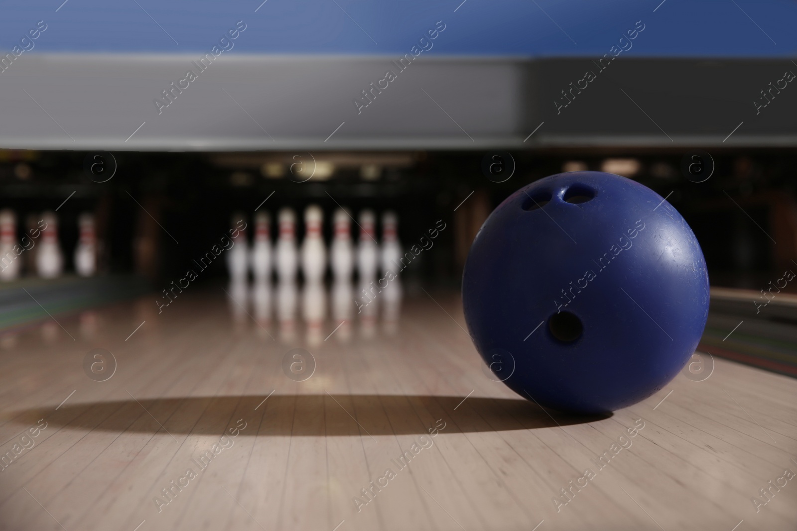 Photo of Blue ball on bowling lane in club. Space for text