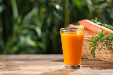 Tasty juice and carrot on wooden table outdoors. Space for text