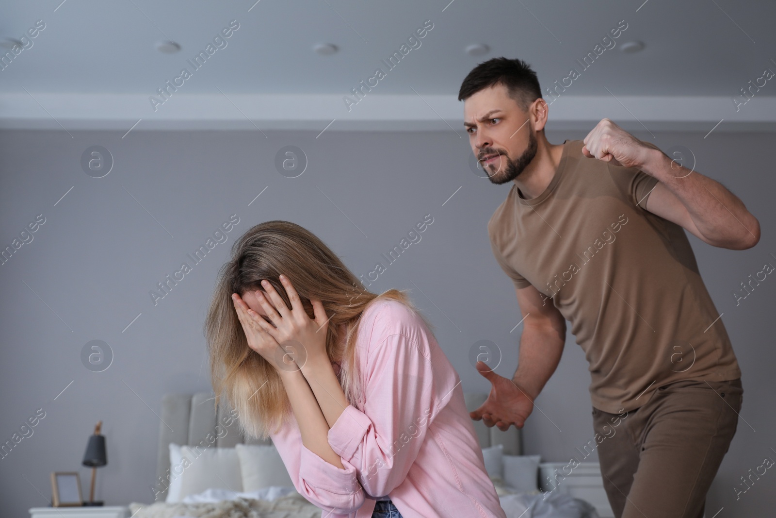 Photo of Man abusing scared woman at home. Domestic violence