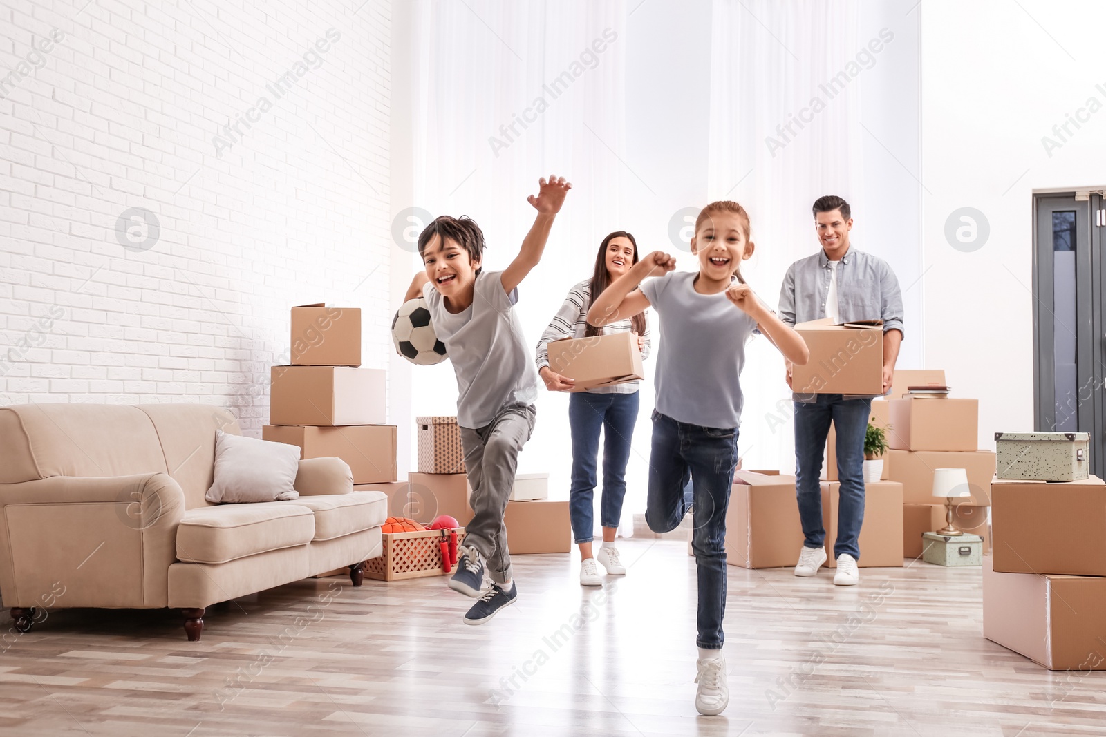 Photo of Happy family in room with cardboard boxes on moving day