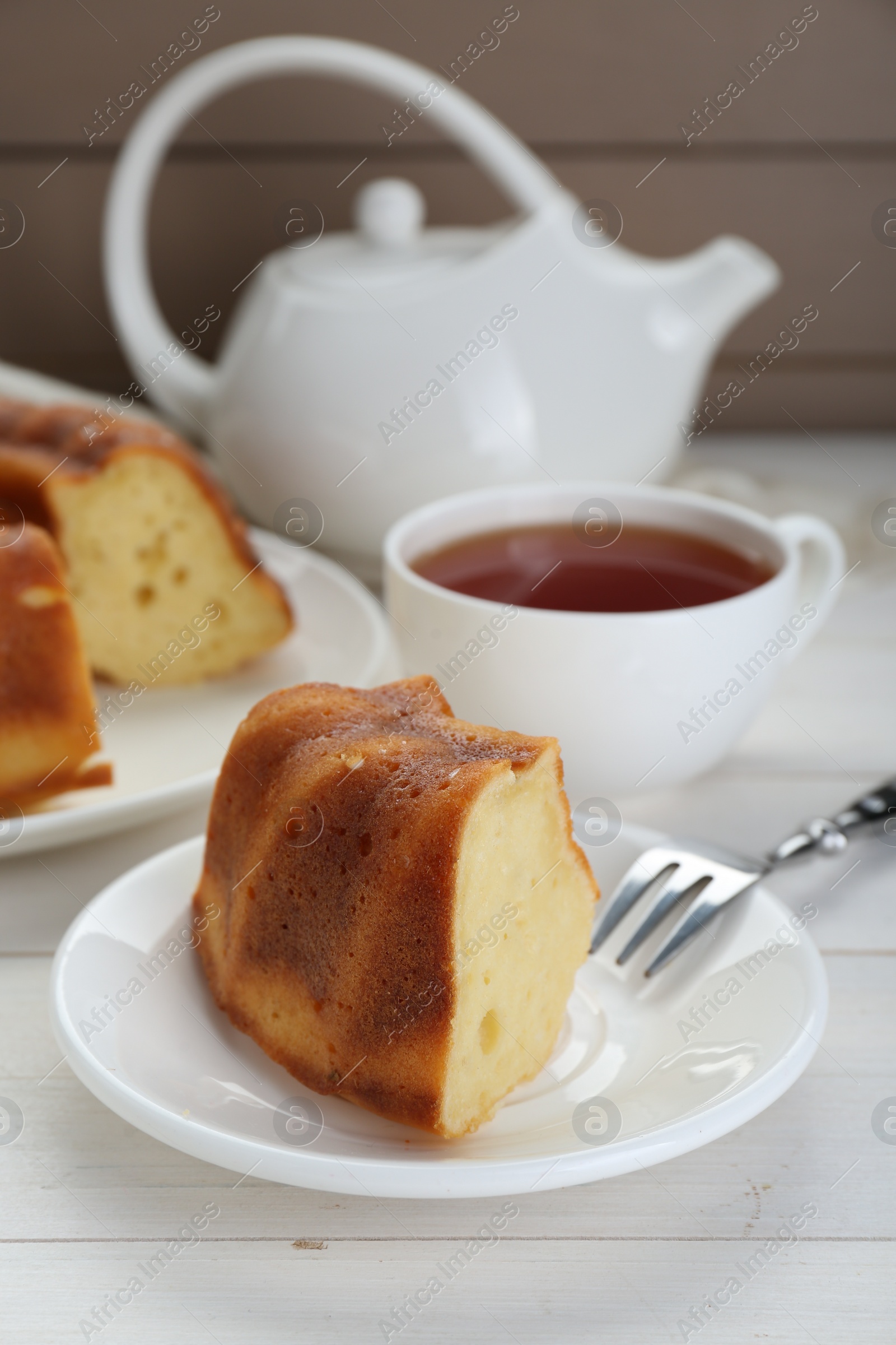 Photo of Piece of delicious homemade yogurt cake served on white wooden table